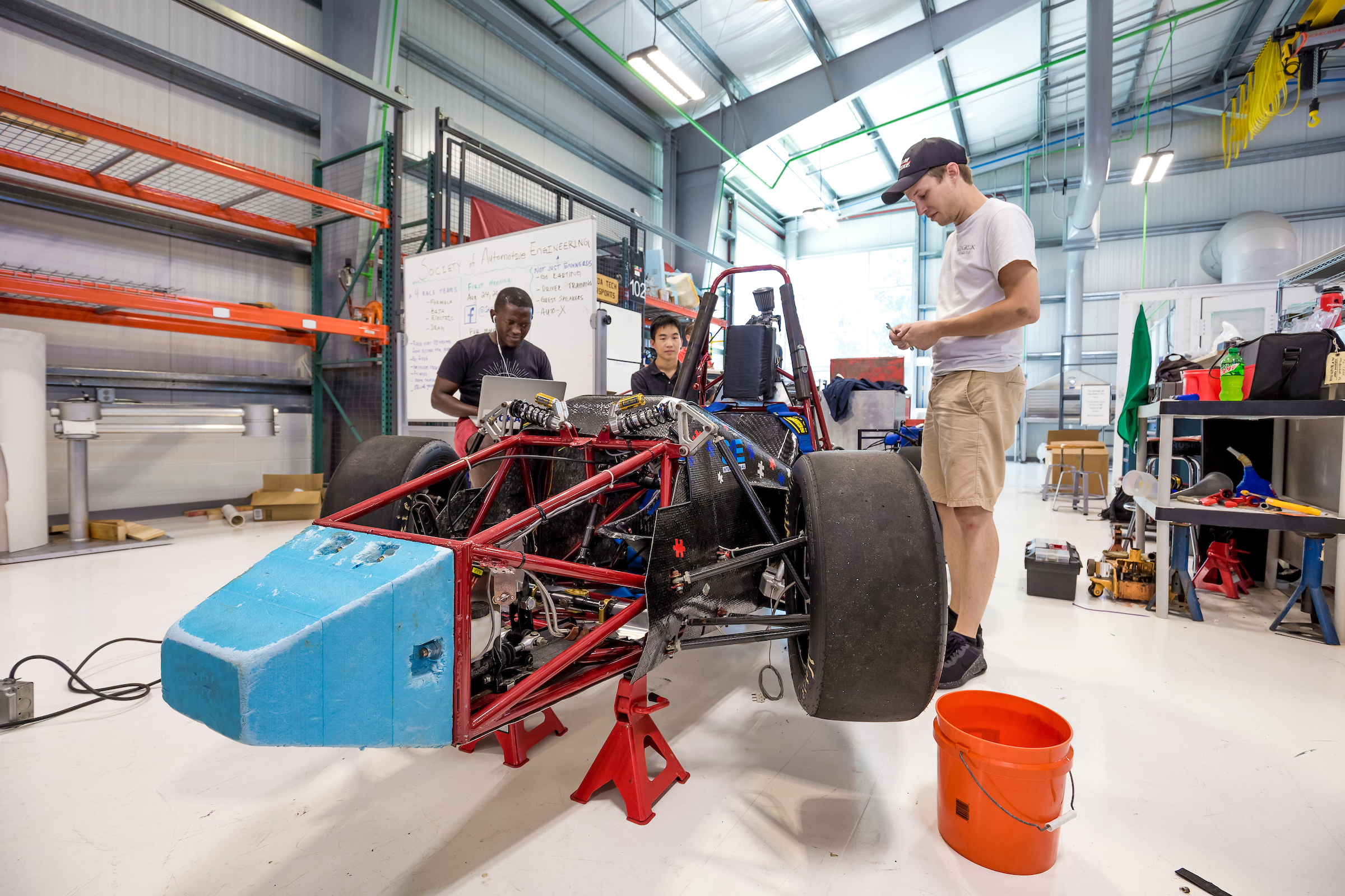 Photo of three students working on a vehicle in an automotive engineering workshop