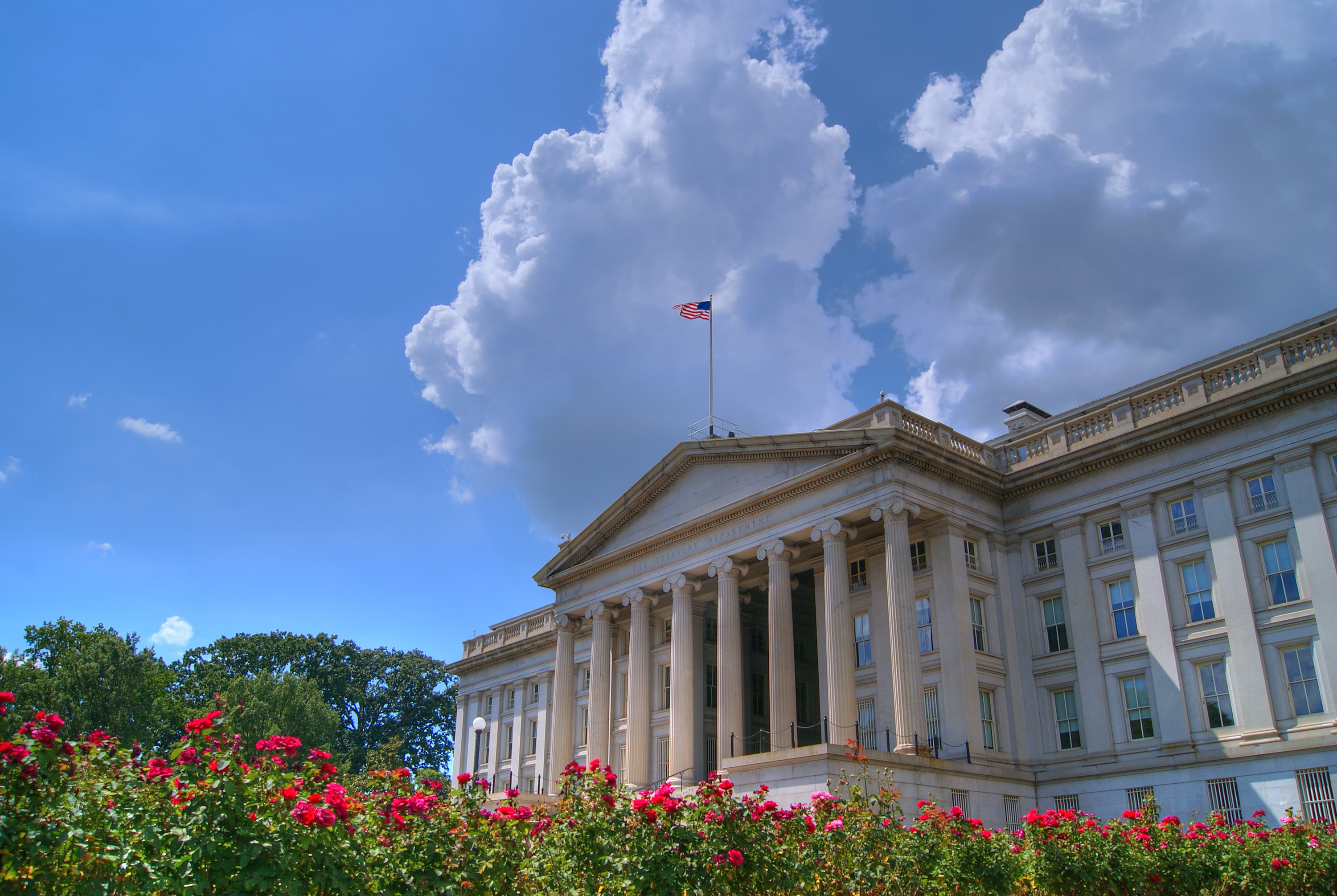 Picture of the US Treasury building with red flowers lining the bottom of the image.