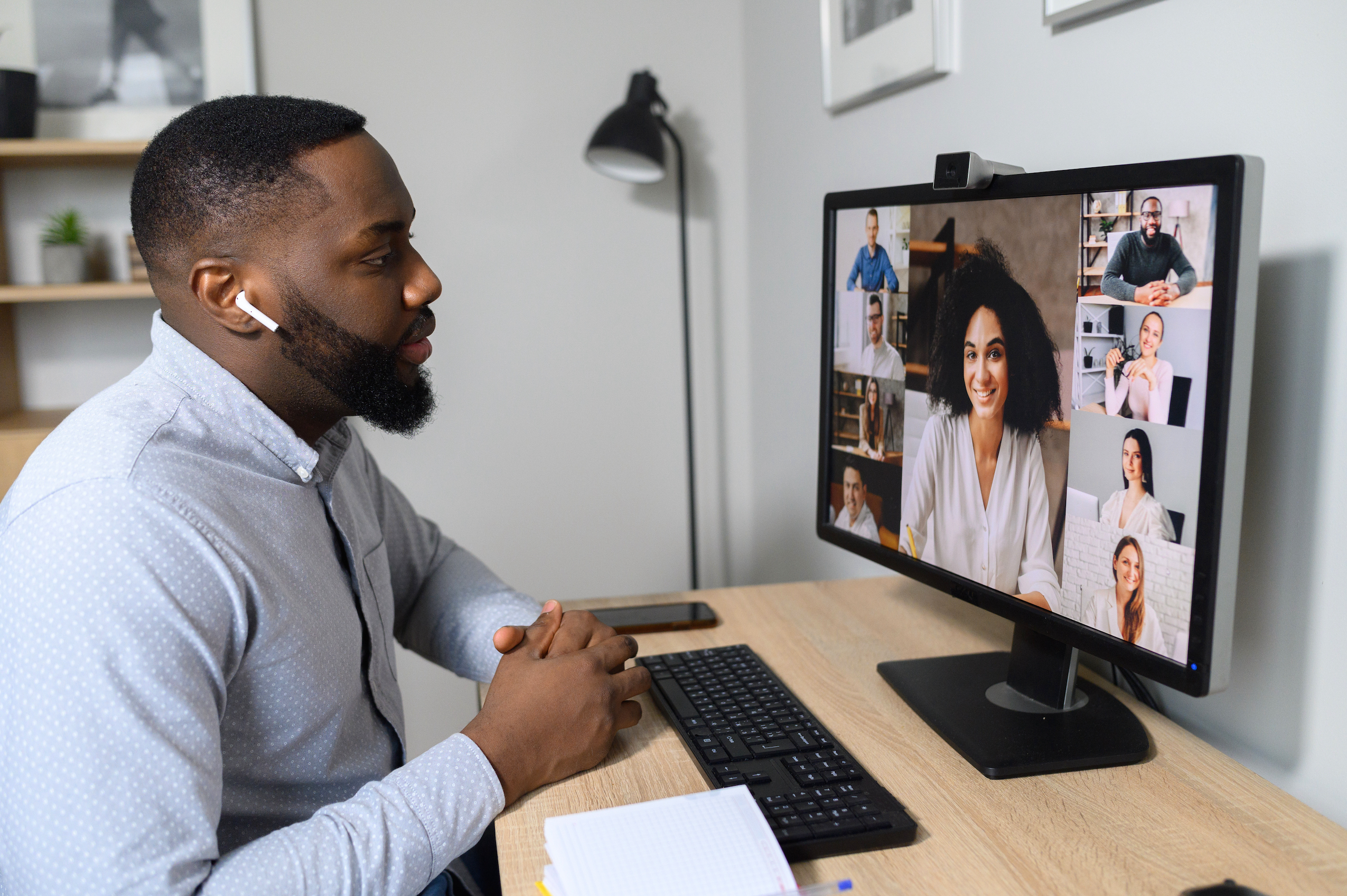 Photo of young man at computer screen participating in virtual meeting