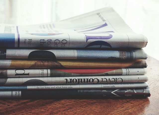 pile of newspapers on a wooden desk