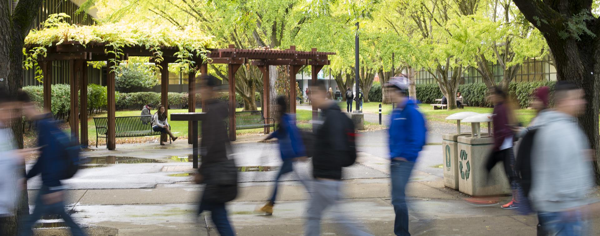 An image on people walking on a college campus where the background is clear and the people are blurry from walking.