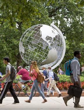 Photo of students passing a Globe sculpture at Kennesaw State University
