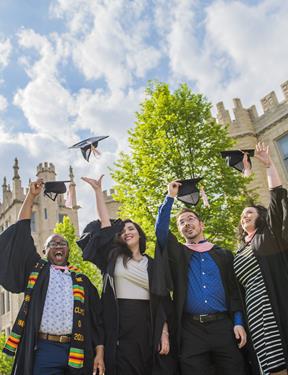 Photo of four new college graduates tossing their caps in celebration