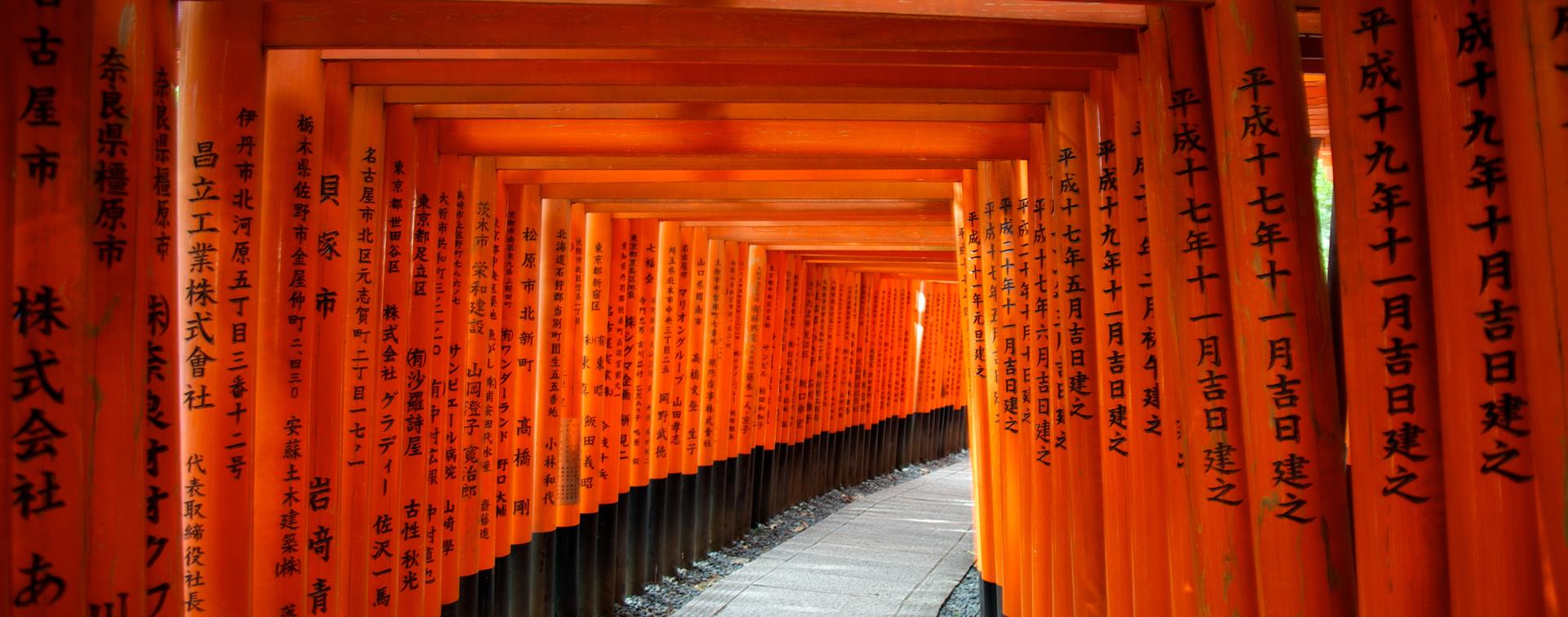 The orange Torii Gates in Japan, with black lettering on them. 