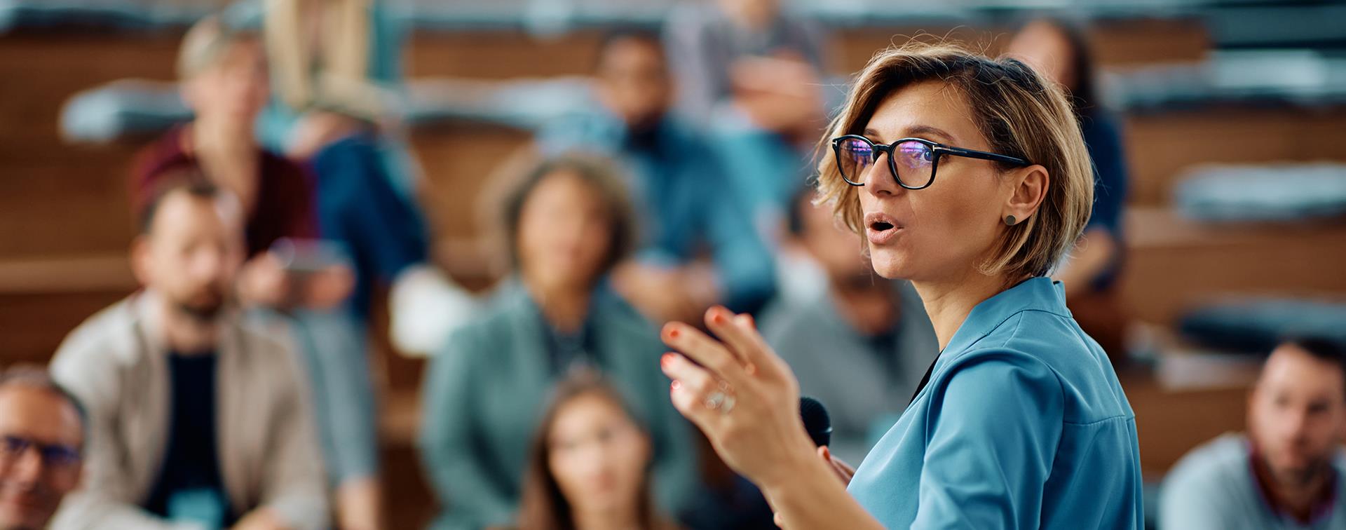 Woman addressing a crowd sitting on bleachers