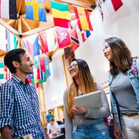 Picture of three students conversing below various hanging national flags