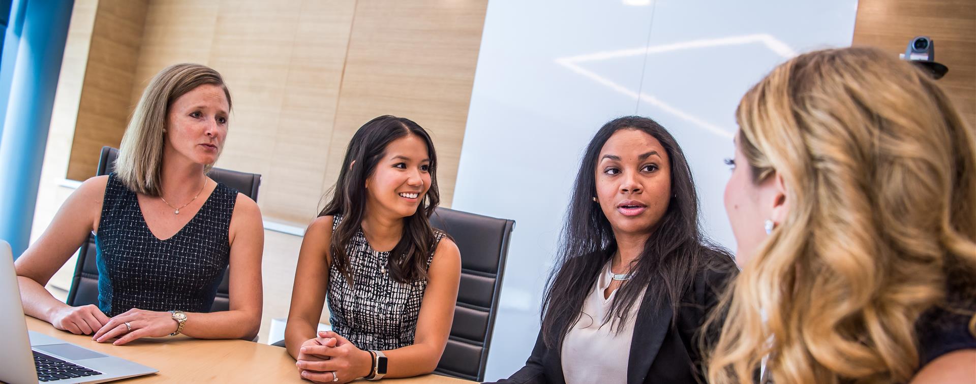 A picture of three women sitting at a table discussing work