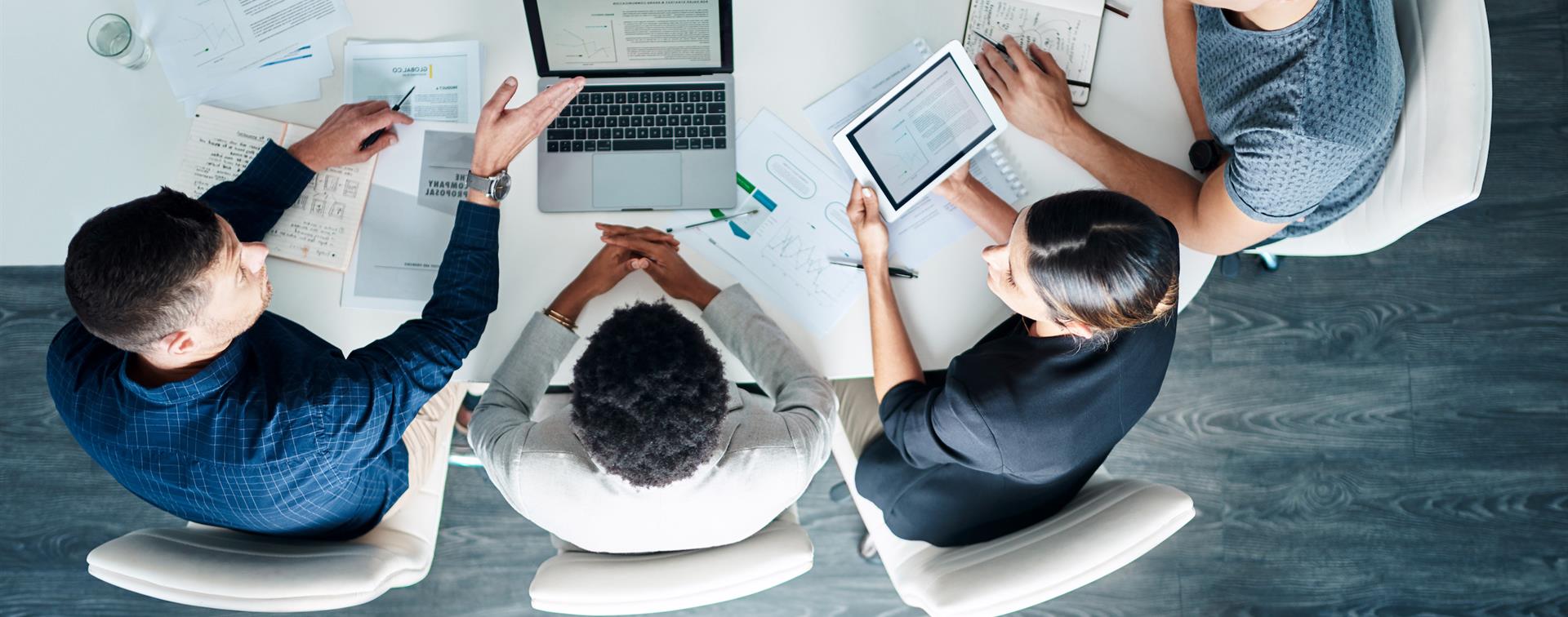 Photo of a group of professionals collaborating around a laoptop and tablet