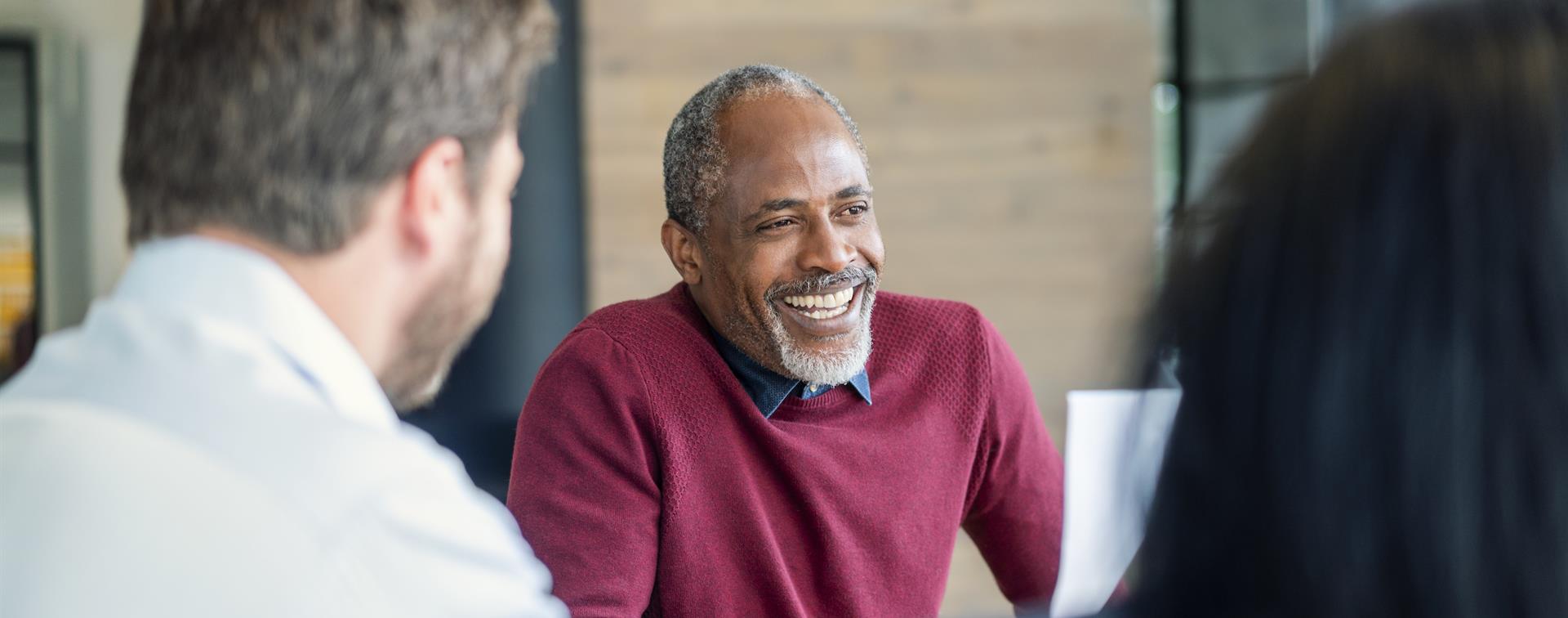 Photo of man laughing with two colleagues in brightly lit office