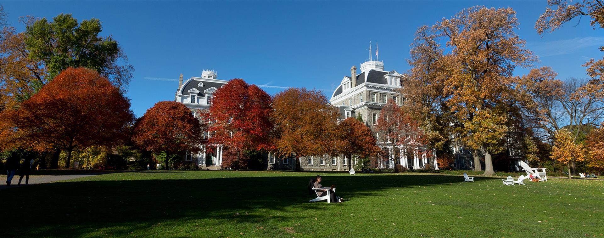 Photo of buildings on a college campus alongside trees full of autumn leaves