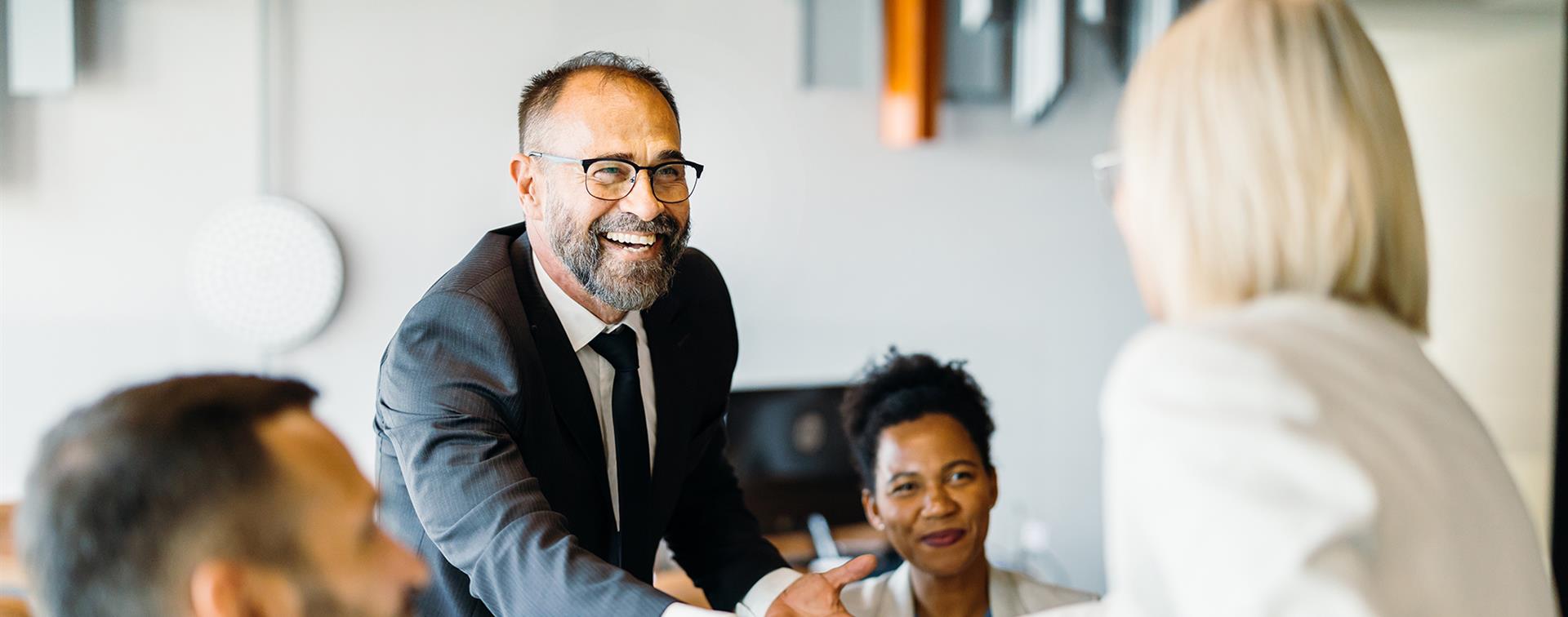 Photo of a smiling man reaching out to shake a woman's hand