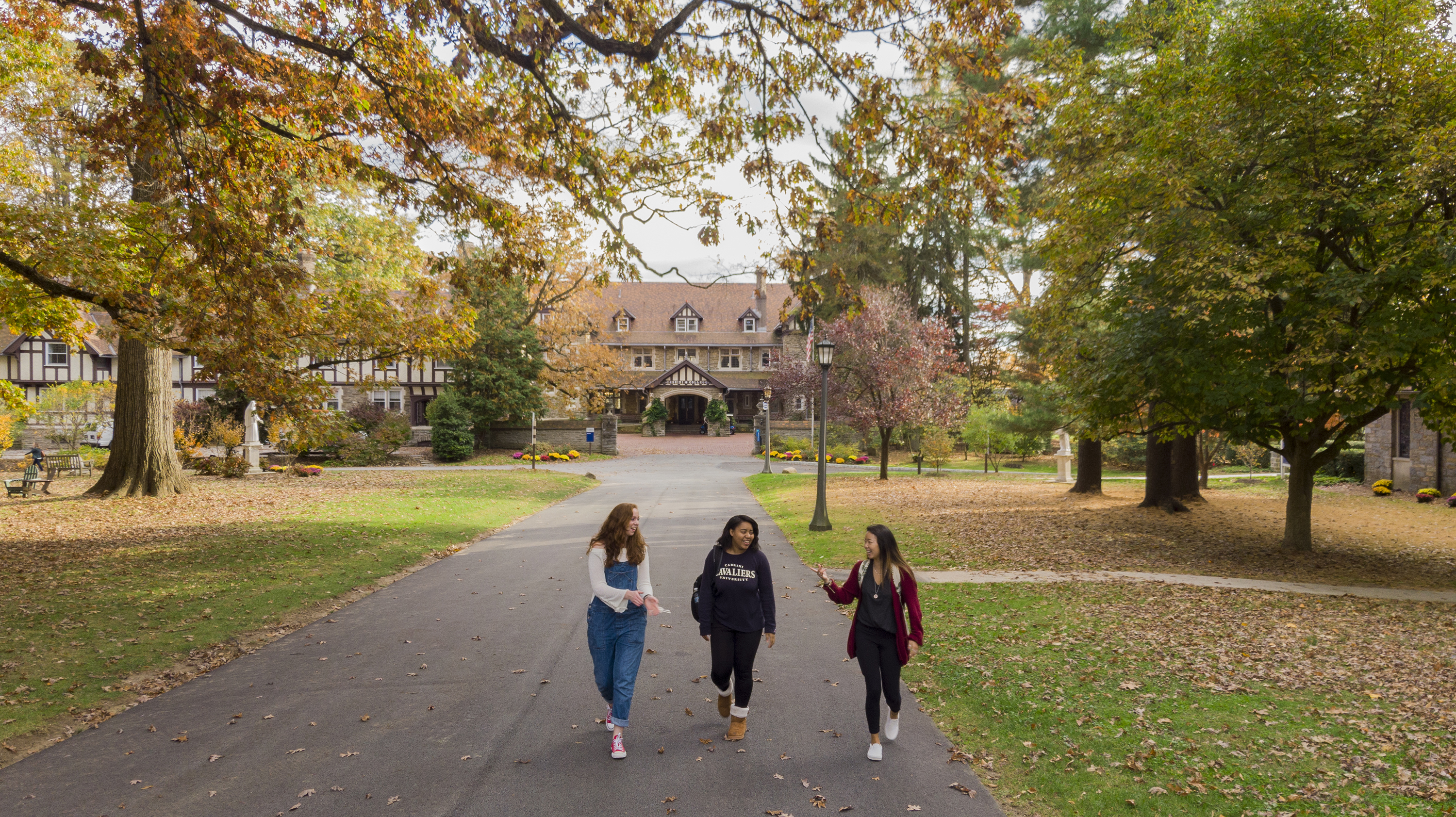 Students walk on a campus on a sunny fall day.