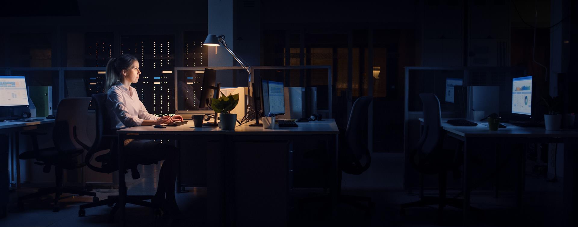 Photo of young professional working after hours in dark office