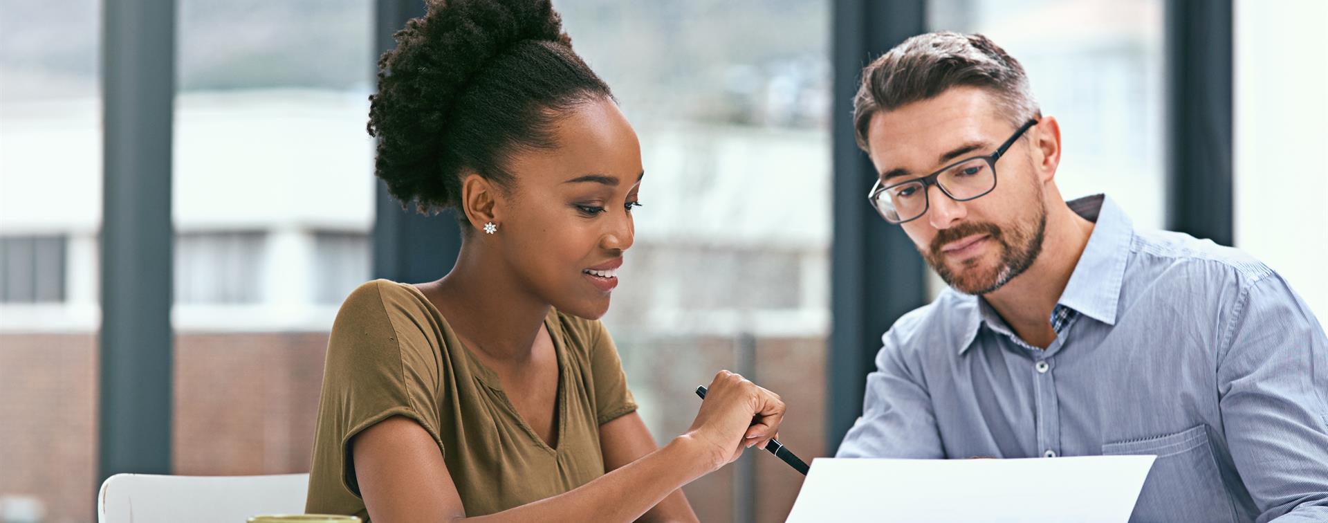 Photo of two colleagues collaborating at a desk in a bright office