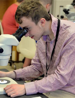 student looking through the lens of a microscope