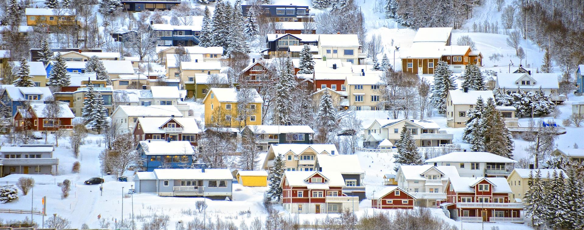 Picture of snowy houses oh a hillside in Tromso, Norway.